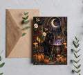 5x7 Gothic black cat Halloween greeting card mockup with brown envelope, crescent moon, cauldron, pumpkins, mushrooms and witch garden