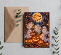 Halloween greeting card product mockup featuring friendly ghosts, pumpkins, bats, a full moon, haunted forest, and brown envelope