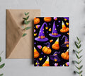 Purple witch hats, orange pumpkins and candy corn on a black 5x7 card beside a kraft envelope